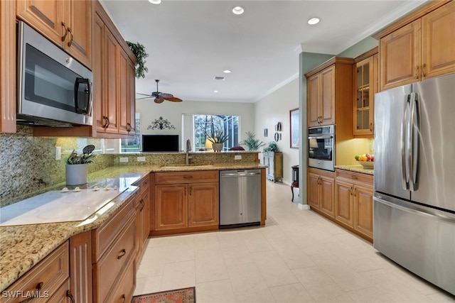 kitchen featuring appliances with stainless steel finishes, brown cabinetry, glass insert cabinets, a sink, and a peninsula