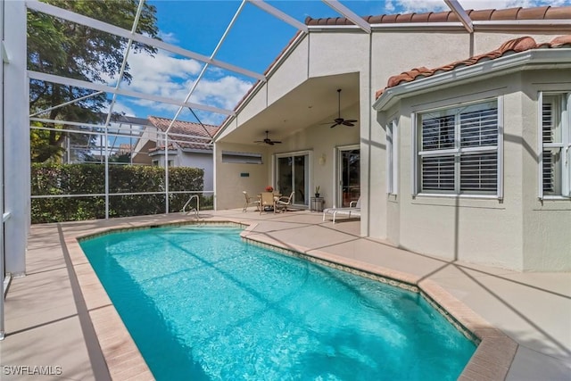 pool featuring glass enclosure, a patio area, and a ceiling fan