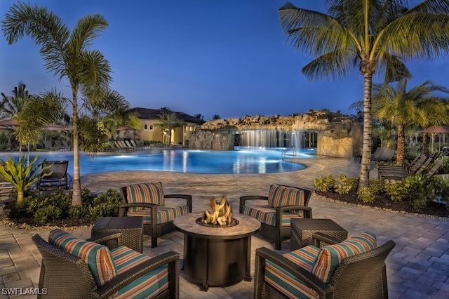 pool at dusk featuring a patio and an outdoor living space with a fire pit