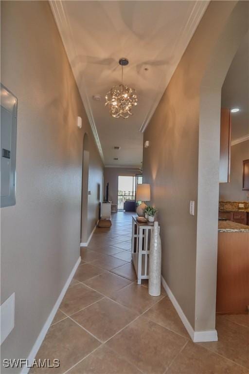 hallway with electric panel, ornamental molding, light tile patterned floors, and an inviting chandelier