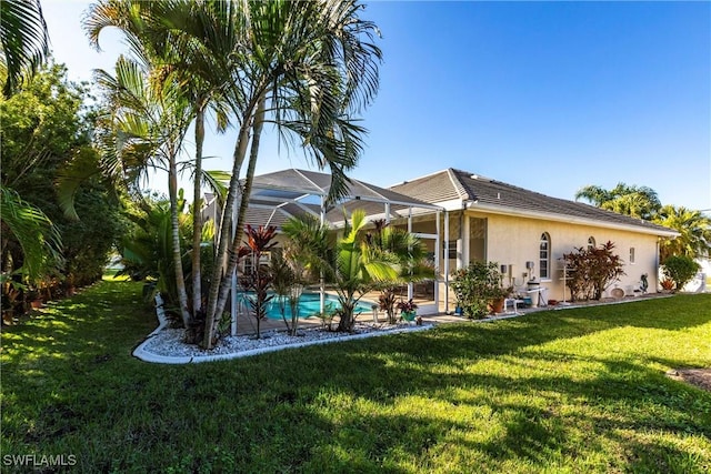 back of house featuring glass enclosure, a lawn, an outdoor pool, and stucco siding