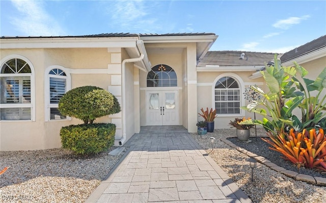 entrance to property with a tiled roof and stucco siding