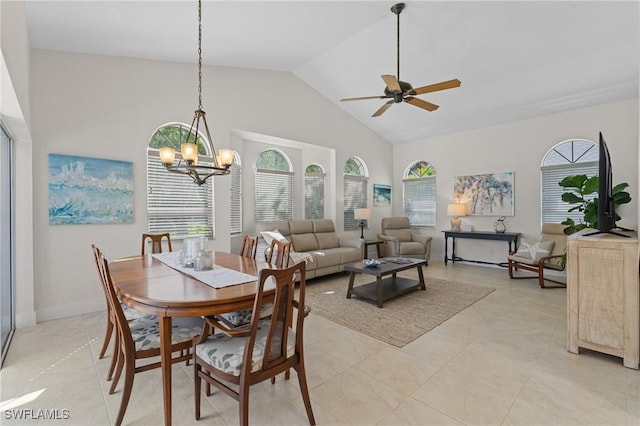 dining space featuring light tile patterned flooring, baseboards, high vaulted ceiling, and ceiling fan with notable chandelier