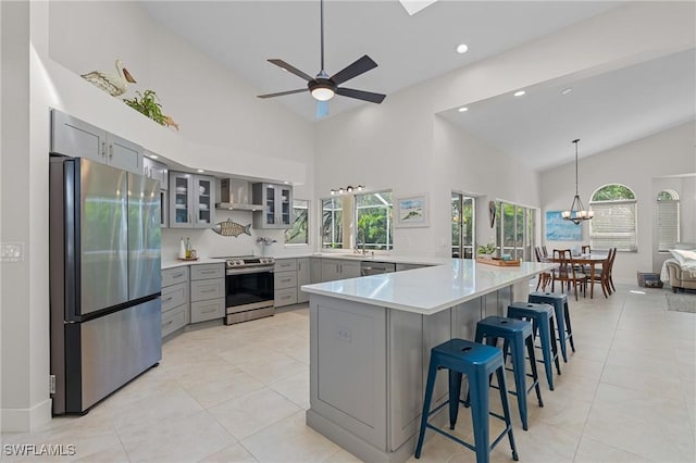 kitchen with stainless steel appliances, light countertops, gray cabinets, a kitchen bar, and glass insert cabinets