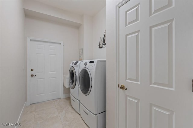 washroom with light tile patterned floors, laundry area, washer and clothes dryer, and baseboards