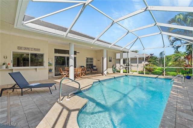 pool featuring glass enclosure, a patio area, and a ceiling fan