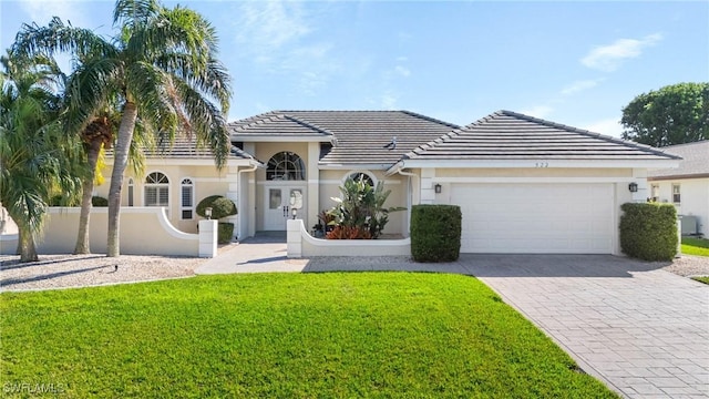 single story home with a tile roof, an attached garage, fence, decorative driveway, and a front yard