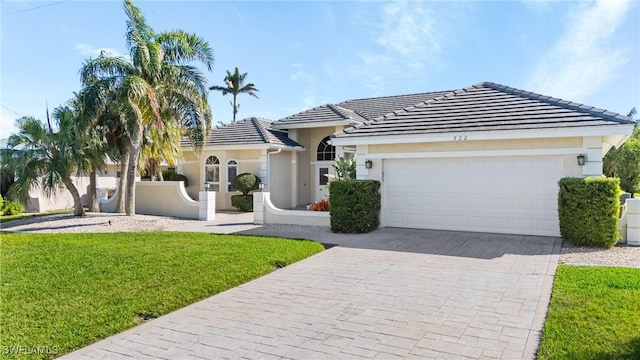 ranch-style house featuring a front lawn, decorative driveway, an attached garage, and stucco siding