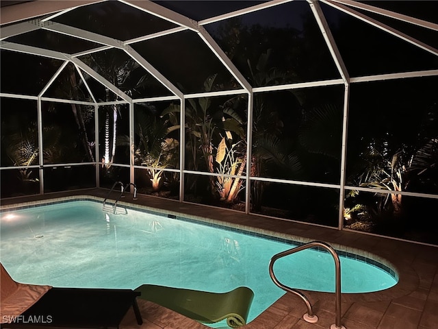 522 SW 51st Ter, Cape Coral, FL 33914 - pool at night featuring glass enclosure, an outdoor pool, and a patio area