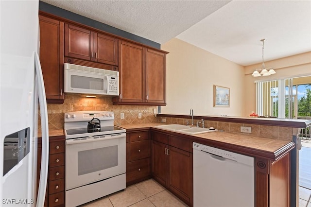 kitchen featuring tile counters, kitchen peninsula, sink, white appliances, and pendant lighting