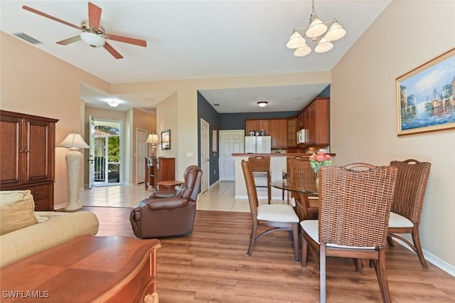 living room with ceiling fan with notable chandelier and light hardwood / wood-style floors