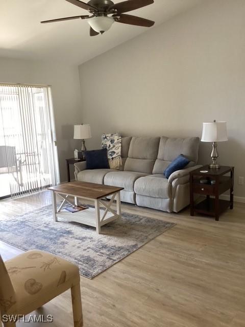 living room with vaulted ceiling, hardwood / wood-style floors, and ceiling fan