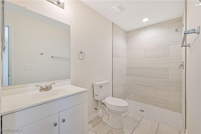 bathroom featuring vanity, tiled shower, toilet, and tile patterned floors