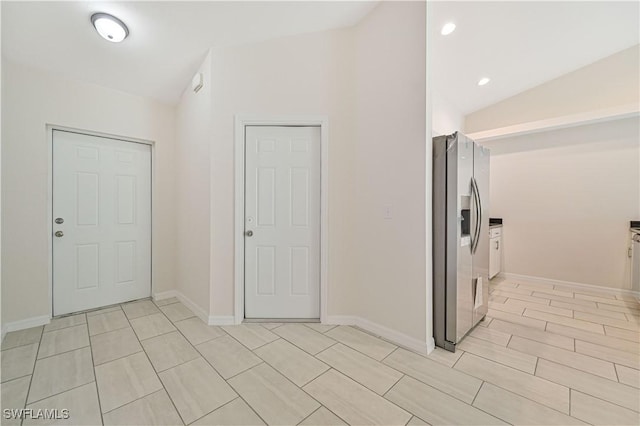 interior space with lofted ceiling and stainless steel fridge