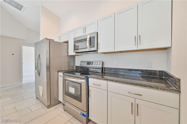 kitchen with white cabinetry, appliances with stainless steel finishes, and dark stone counters