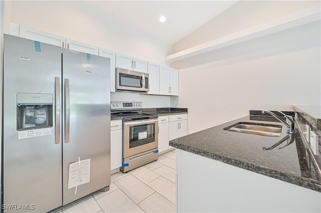 kitchen featuring stainless steel appliances, white cabinets, vaulted ceiling, light tile patterned floors, and sink