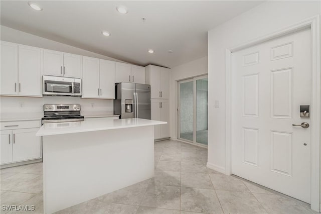 kitchen with stainless steel appliances, a kitchen island, light countertops, and white cabinetry