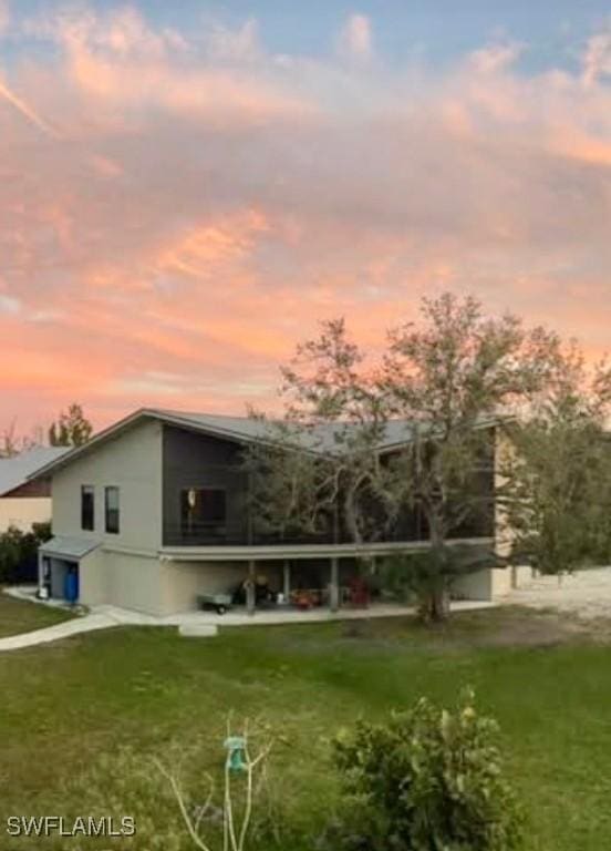 back house at dusk featuring a lawn