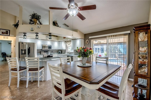 dining space with vaulted ceiling, light tile patterned flooring, visible vents, and a ceiling fan