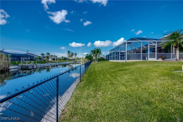 view of yard with a water view, glass enclosure, and fence