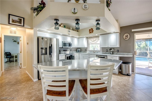 kitchen with visible vents, white cabinets, a kitchen breakfast bar, stainless steel appliances, and a sink