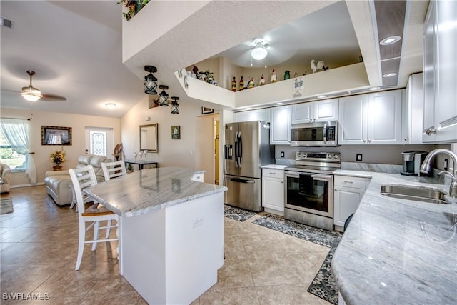 kitchen with visible vents, a ceiling fan, a breakfast bar, stainless steel appliances, and a sink