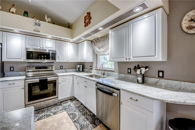 kitchen with stainless steel appliances, white cabinetry, a sink, and light tile patterned flooring