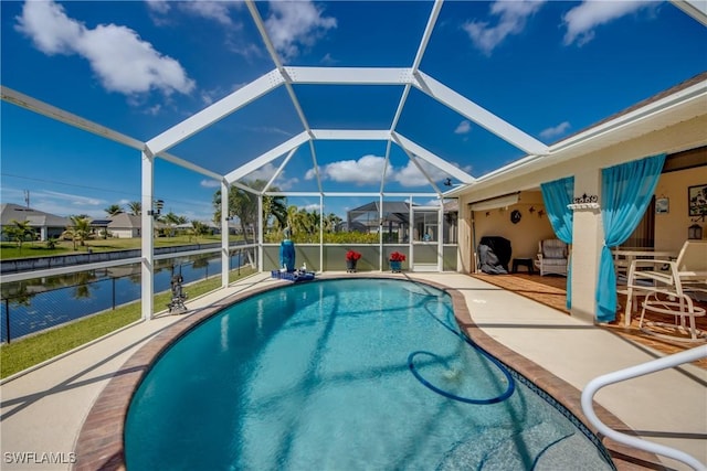 pool with a patio area, glass enclosure, and a water view