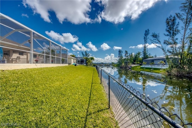 view of yard with glass enclosure, a water view, and fence