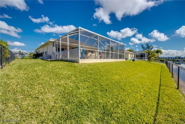 back of property with glass enclosure, a lawn, and fence