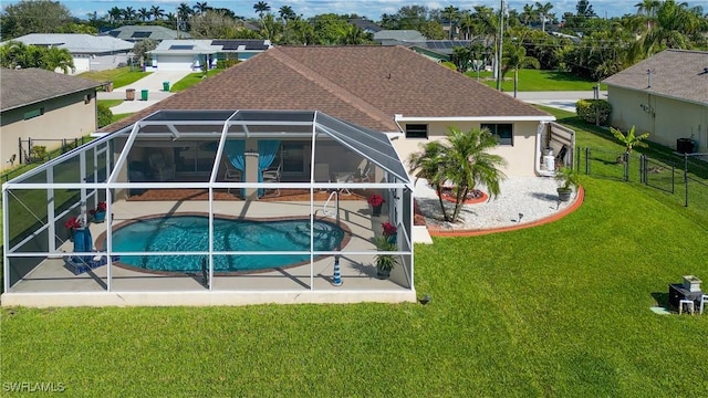 back of property featuring a patio, a shingled roof, a lawn, fence, and a lanai