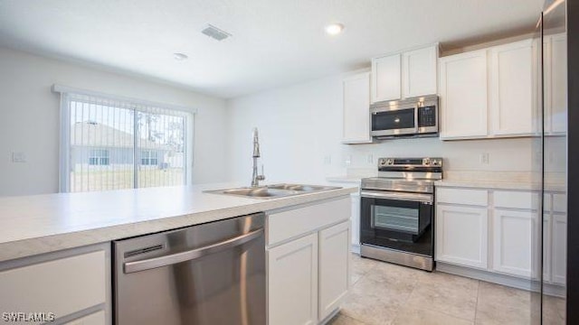 kitchen with light tile patterned floors, sink, stainless steel appliances, and white cabinetry