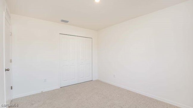 unfurnished bedroom with a closet and light colored carpet