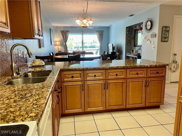 kitchen with sink, kitchen peninsula, stove, and hanging light fixtures