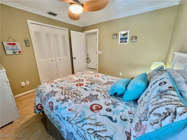 bedroom with ornamental molding, light hardwood / wood-style flooring, ceiling fan, and a closet