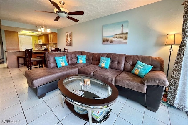 living room with a textured ceiling, ceiling fan with notable chandelier, and light tile patterned floors