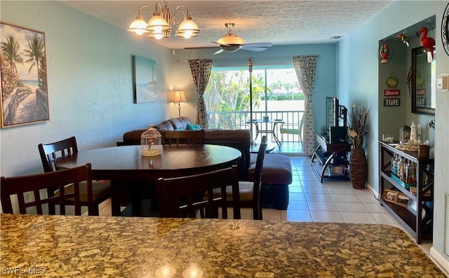 dining space featuring ceiling fan with notable chandelier, light tile patterned floors, and a textured ceiling