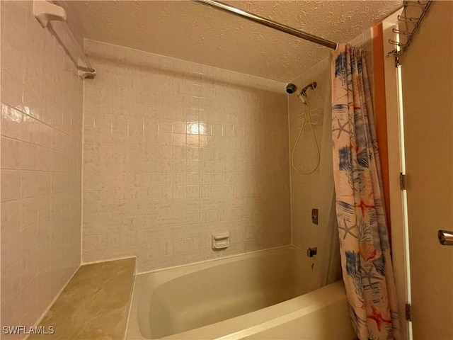 bathroom with shower / bath combination with curtain and a textured ceiling