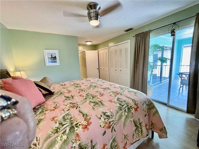 bedroom with access to exterior, hardwood / wood-style floors, ceiling fan, and multiple closets