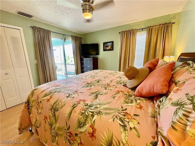 bedroom featuring ceiling fan, access to outside, a textured ceiling, and a closet