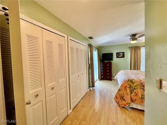 bedroom with light hardwood / wood-style flooring and two closets