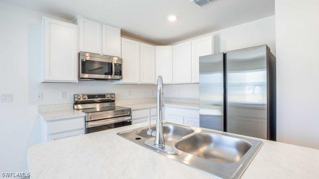 kitchen featuring appliances with stainless steel finishes, sink, and white cabinetry