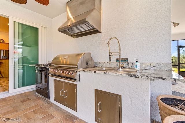 15791 Quail Trl, Bokeelia, FL 33922 - kitchen with a sink, wall chimney range hood, a textured wall, and stone tile flooring