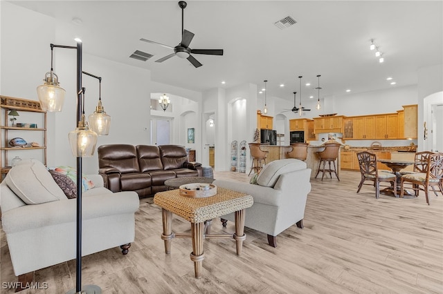 15791 Quail Trl, Bokeelia, FL 33922 - living area featuring arched walkways, ceiling fan with notable chandelier, visible vents, and light wood-type flooring