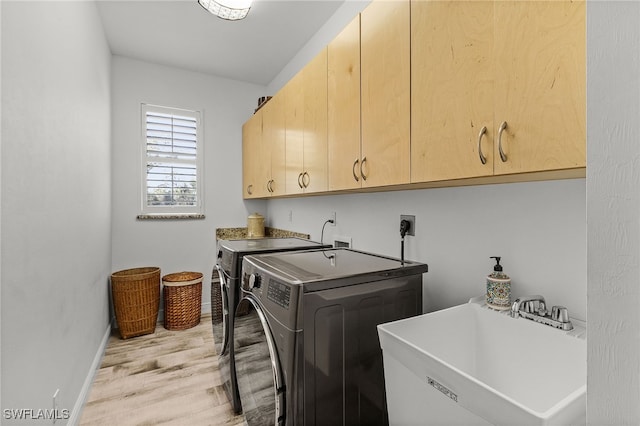 15791 Quail Trl, Bokeelia, FL 33922 - clothes washing area featuring baseboards, light wood-type flooring, washer and clothes dryer, cabinet space, and a sink