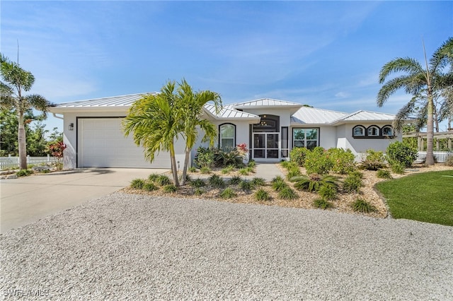 view of front of property with metal roof, an attached garage, driveway, stucco siding, and a standing seam roof