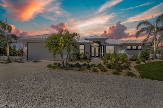 15791 Quail Trl, Bokeelia, FL 33922 - view of front facade with driveway, an attached garage, metal roof, stucco siding, and a standing seam roof