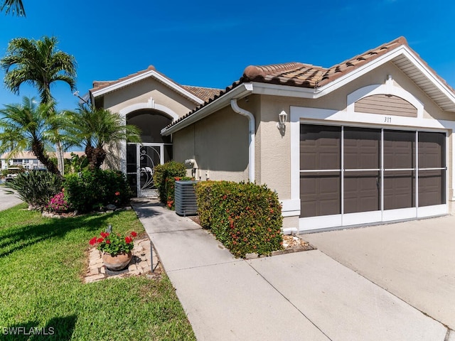 view of front of property with a garage, central AC unit, and a front lawn