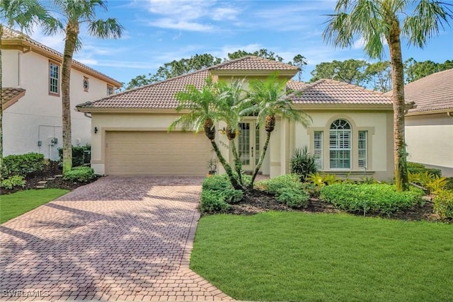 mediterranean / spanish house featuring decorative driveway, a tile roof, stucco siding, a garage, and a front lawn