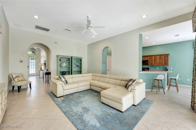 living area featuring light tile patterned floors, visible vents, and arched walkways